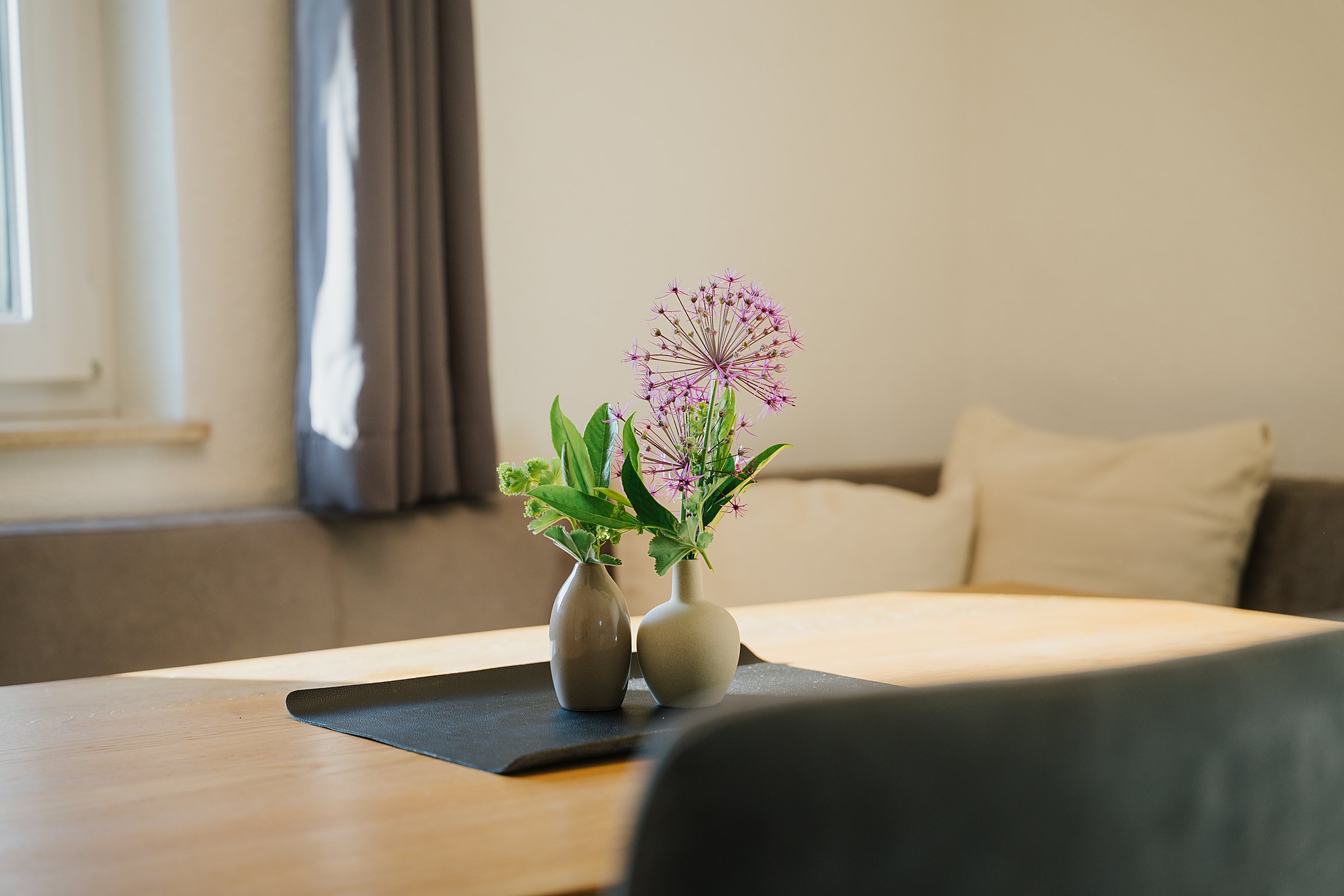 Heller Wohnbereich mit Sofa, Holzboden und frischen Blumen im Ferienhaus Gnesau